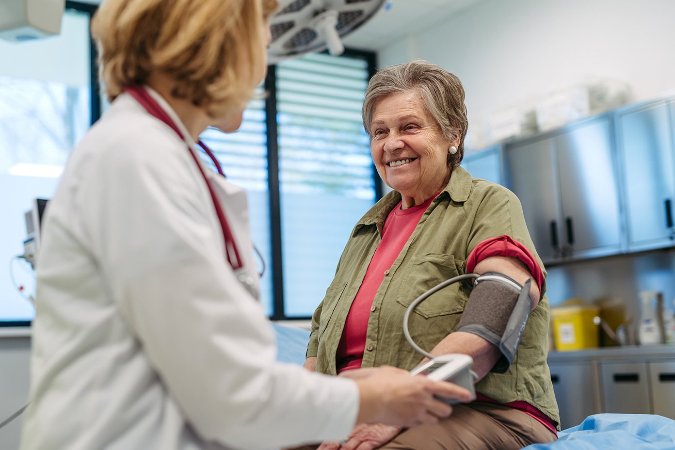 Smiling older woman having her blood pressure checked by a doctor during a clinic visit